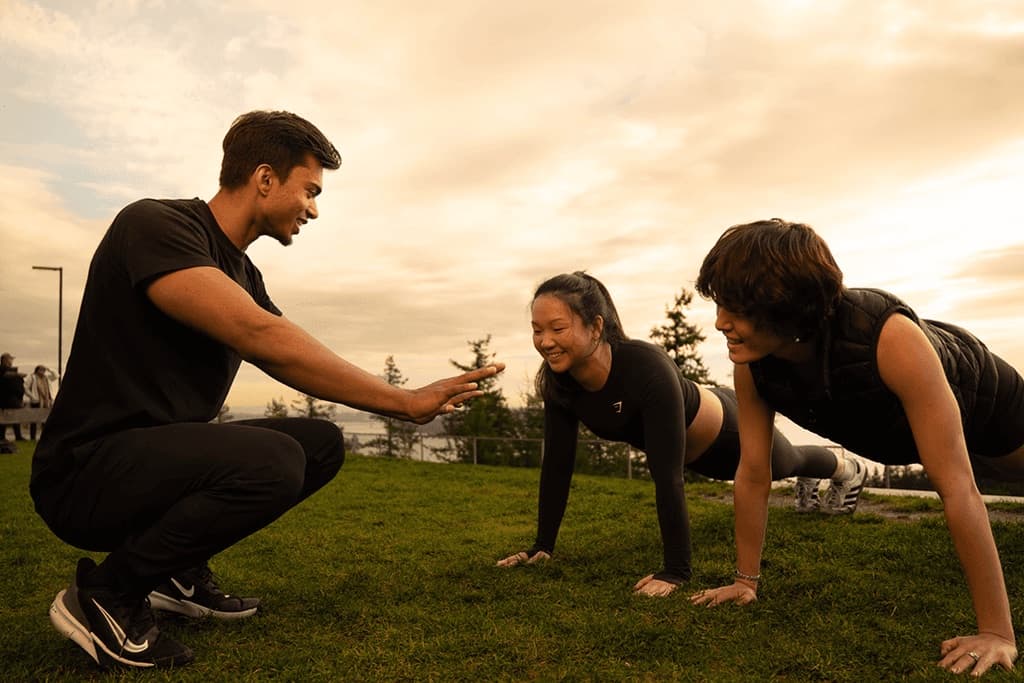 Saran coaching two clients in a plank at sunset